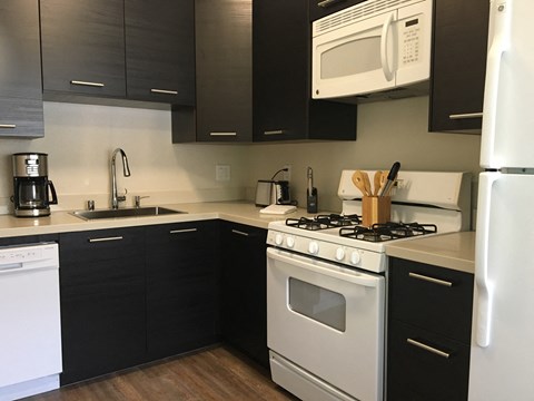 a kitchen with white appliances and black cabinets and a white refrigerator