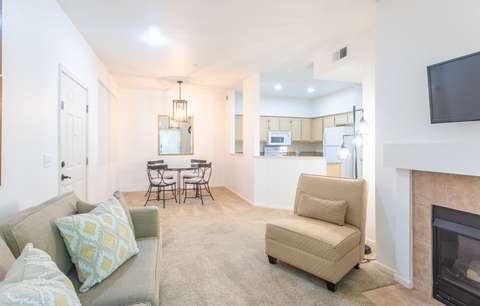 a living room with a fireplace and a kitchen with a table and chairs