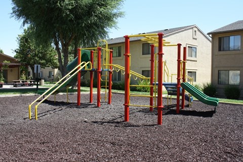 A playground with a red and yellow structure and a green slide.