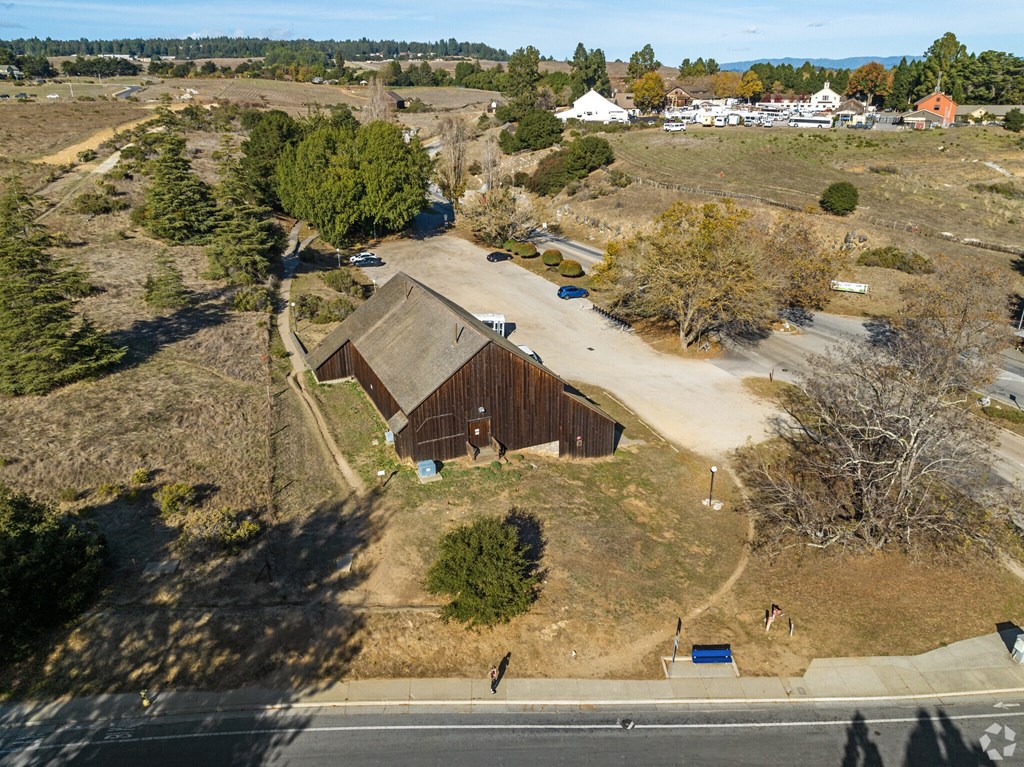 A large barn sits in the middle of a field with a road running in front of it at Westmont Place Townhomes Apartments, Santa Cruz, CA, 95060