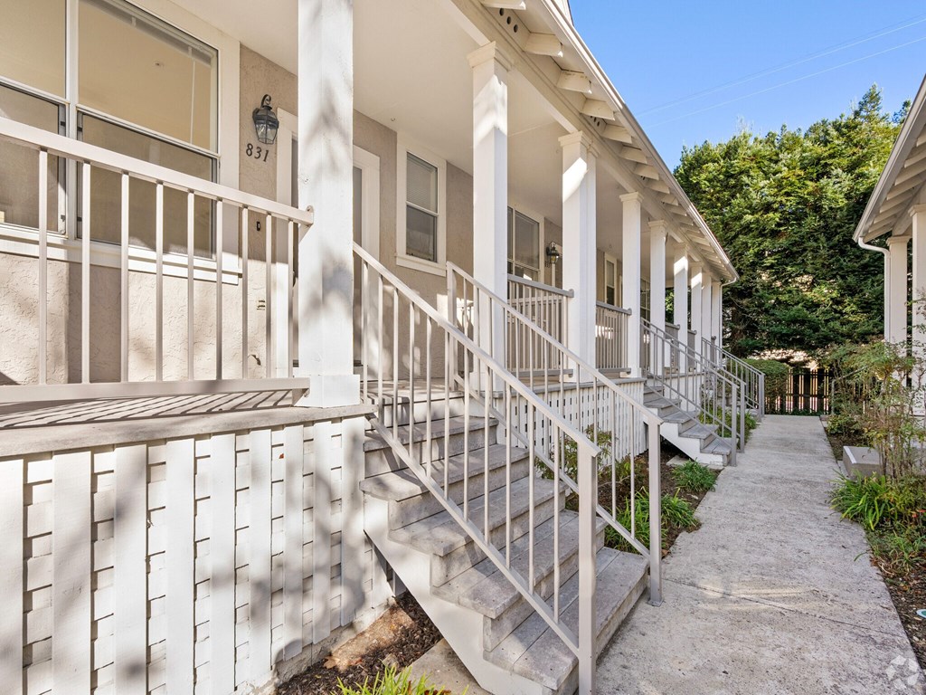 A white building with a balcony and steps leading to the front door at Westmont Place Townhomes Apartments, Santa Cruz, CA