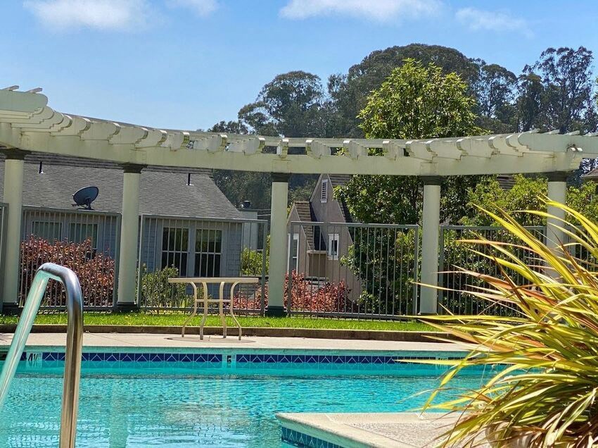 A pool with a slide and a house in the background at Westmont Place Townhomes Apartments, Santa Cruz