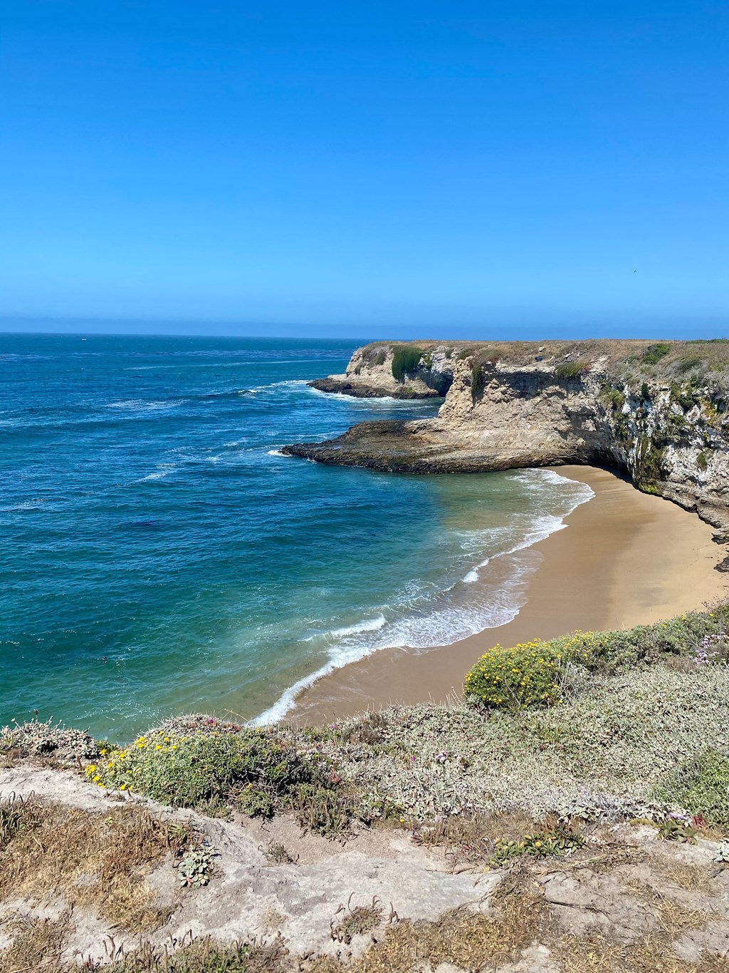 A beach with a cliff and ocean in the background at Westmont Place Townhomes Apartments, California, 95060