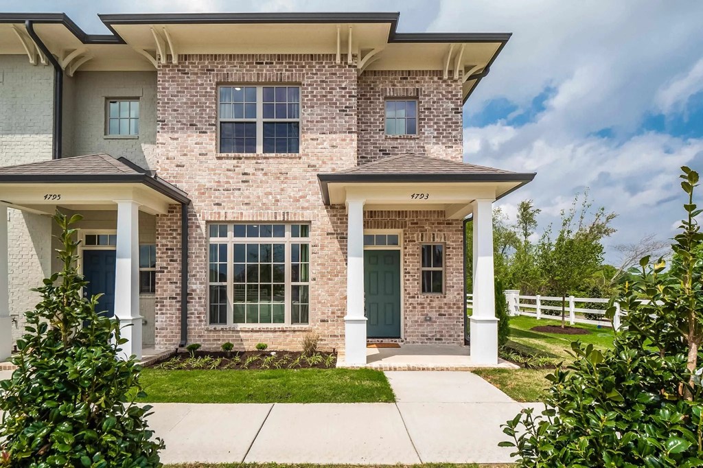 the front of a brick townhome with a sidewalk in front of it