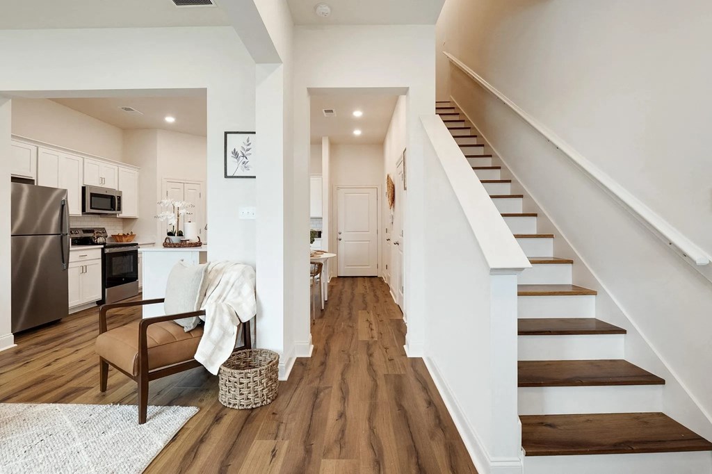 a living room with a staircase next to a kitchen