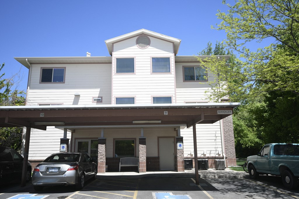 the front of a white house with cars parked in a parking lot