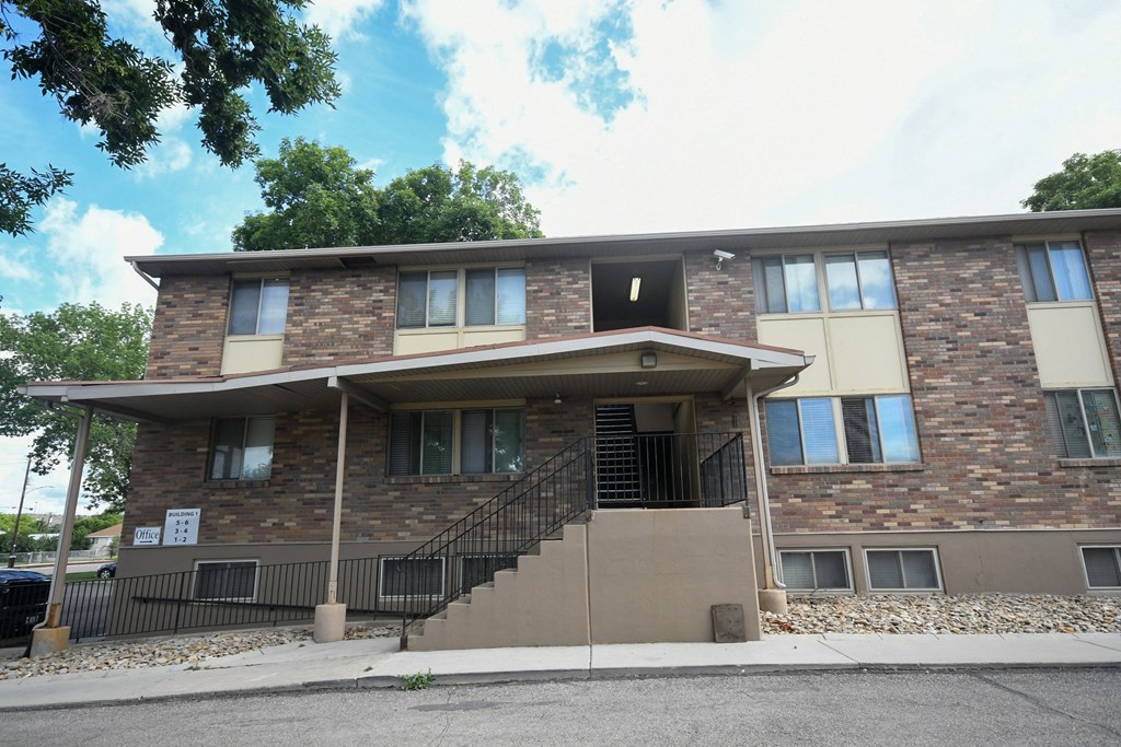 the front of a brick building with stairs and a porch