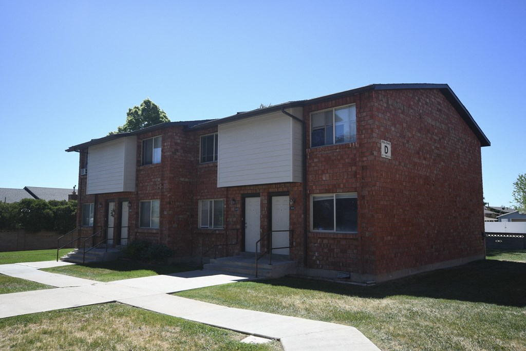 a red brick house with white siding and a sidewalk