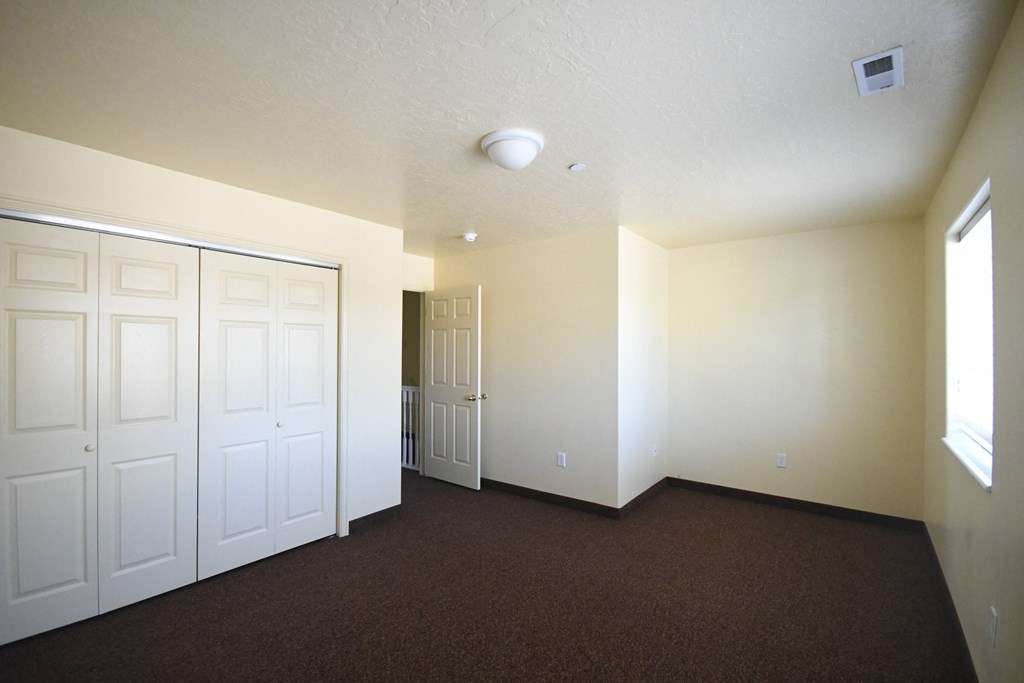 an empty living room with two closets and a door to a hallway