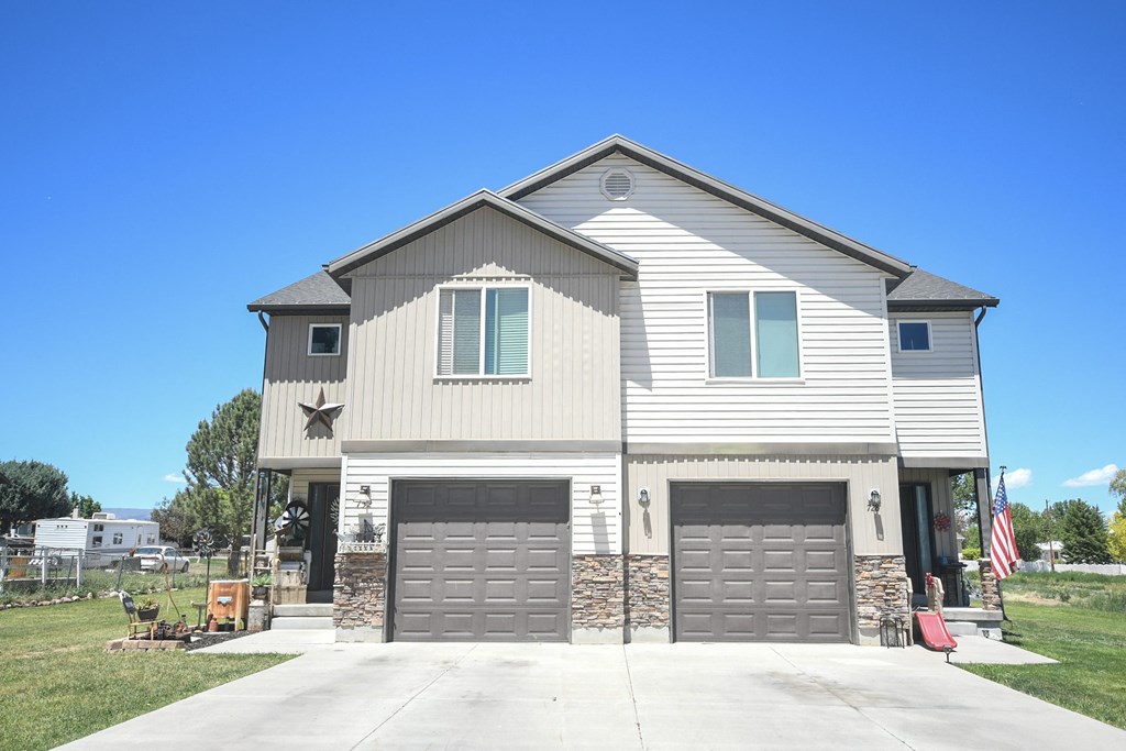 a white house with two garage doors and a blue sky
