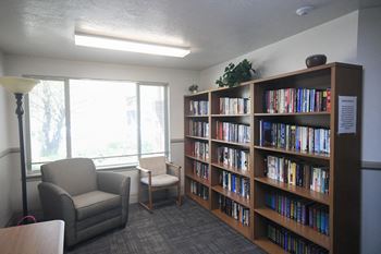 a library with two chairs and a large book shelf