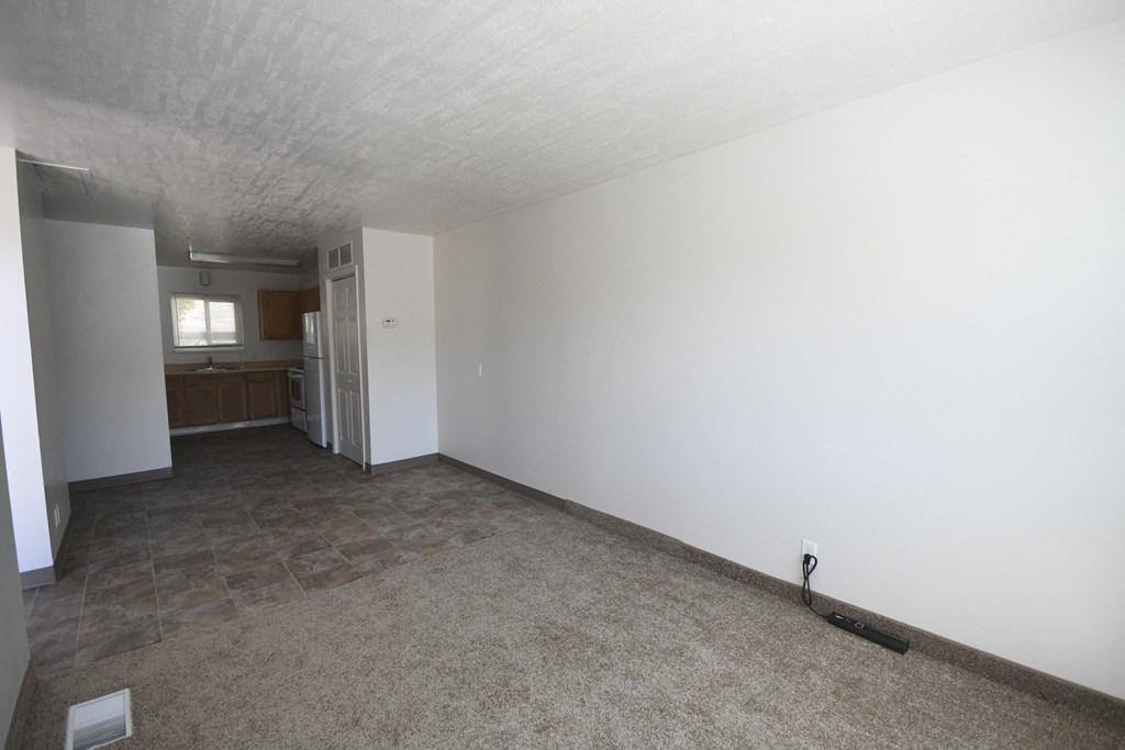 an empty living room and kitchen with white walls and flooring