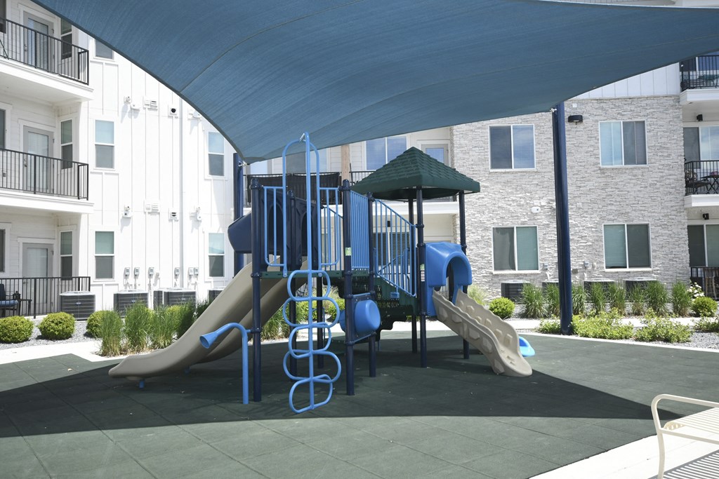 a playground at an apartment complex with a blue canopy over it
