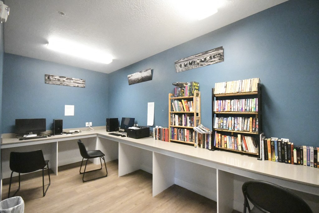 a library with two long desks with bookshelves and computers