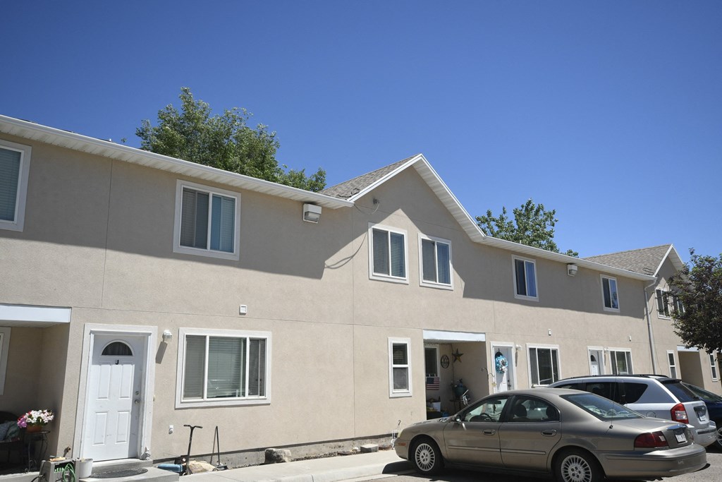 the exterior of a tan building with cars parked outside