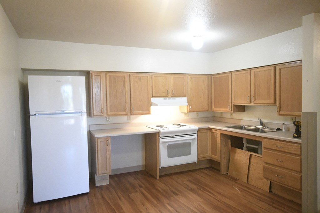 an empty kitchen with wooden cabinets and a white refrigerator