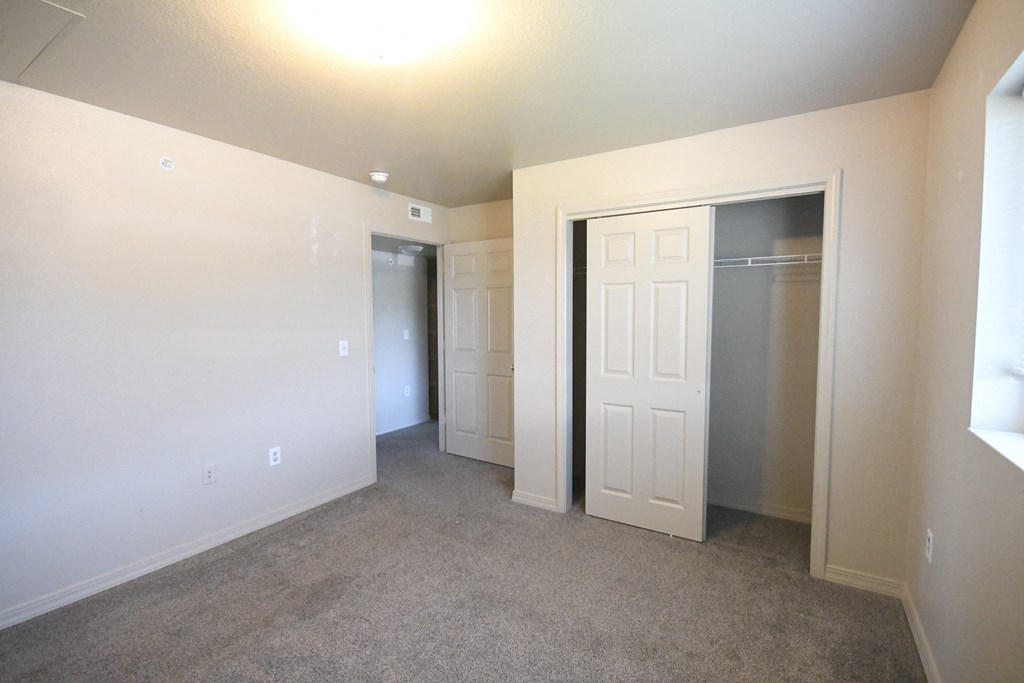 an empty living room with a closet and a door to a bedroom