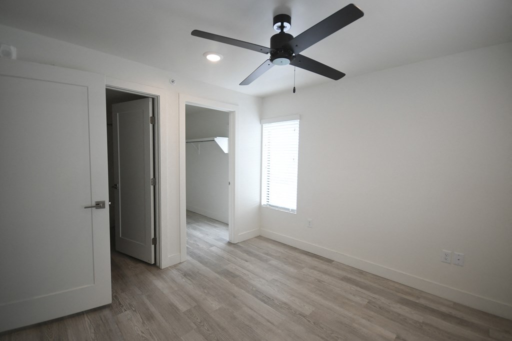 a living room with white walls and a ceiling fan