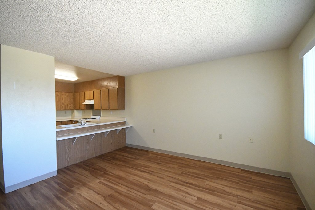 an empty living room and kitchen with wood flooring