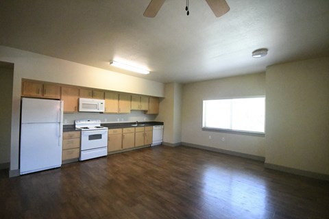 an empty kitchen with wooden floors and white appliances