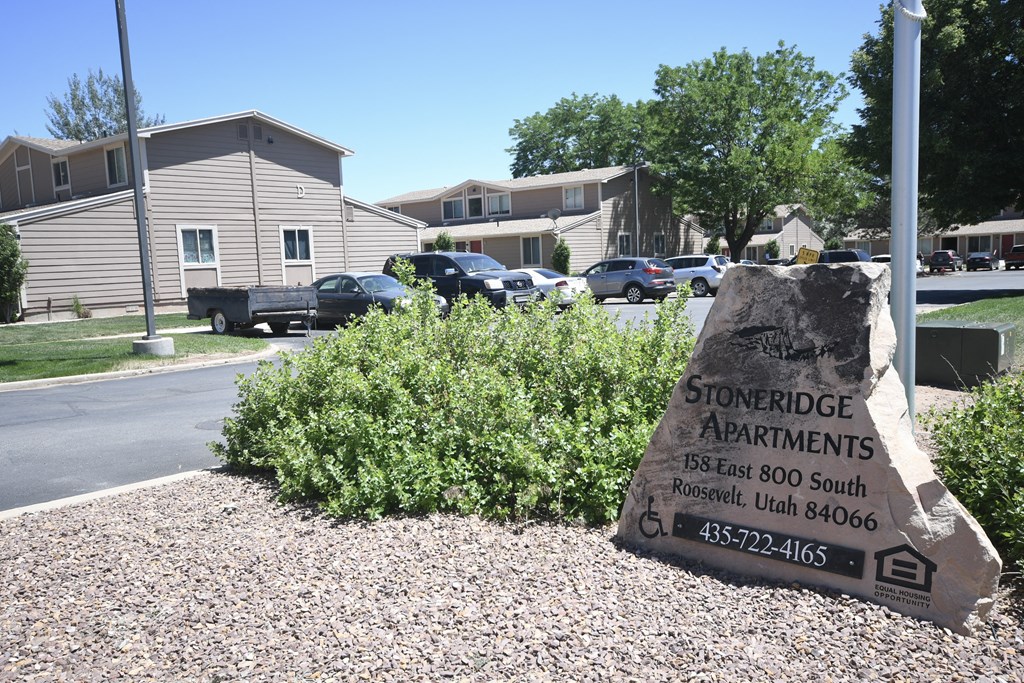 a stone sign for stoneridge apartments on the side of a street