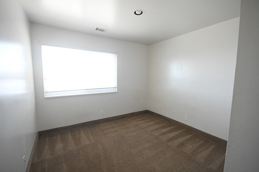 an empty room with a window and a carpet