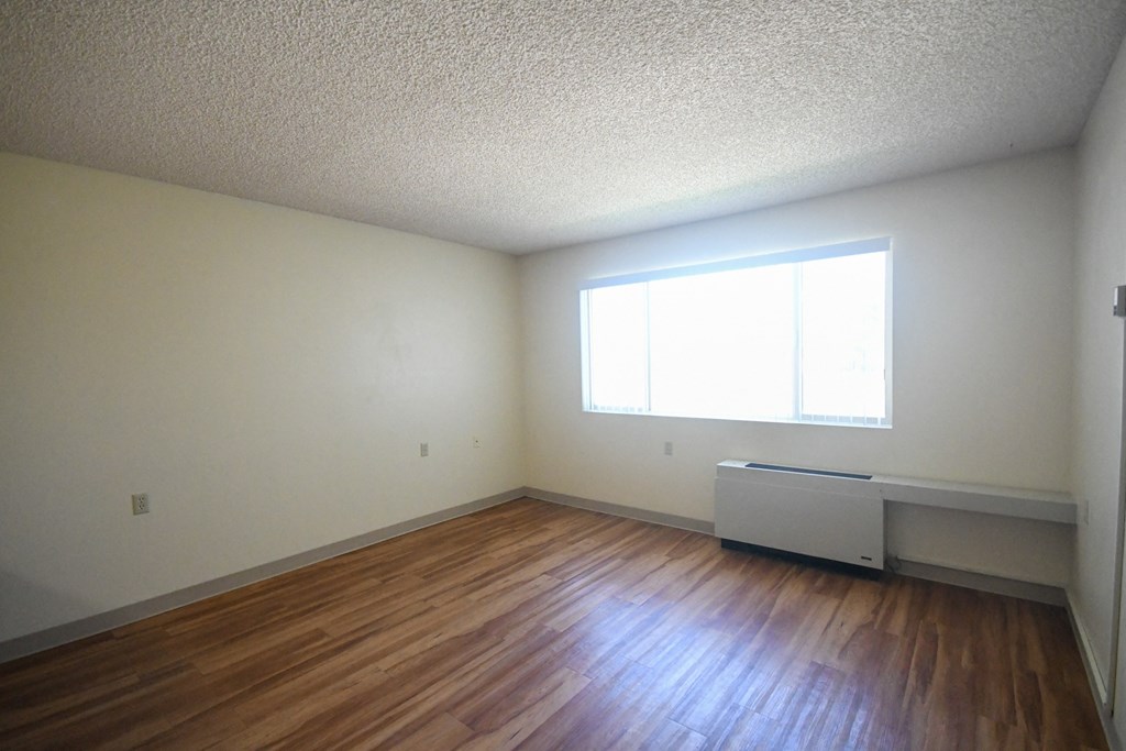 an empty living room with wood floors and a window