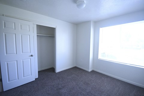 an empty bedroom with a closet and a window