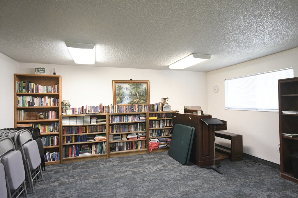 a library with bookshelves and chairs and a desk