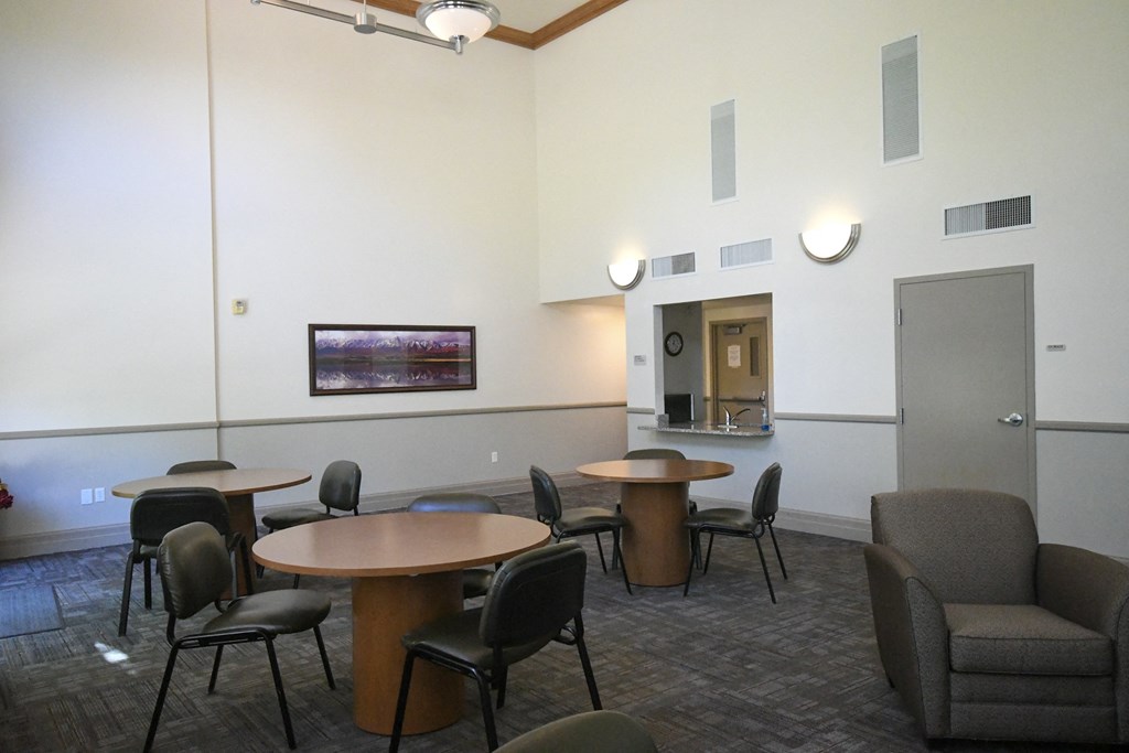 a large room with tables and chairs and a kitchen