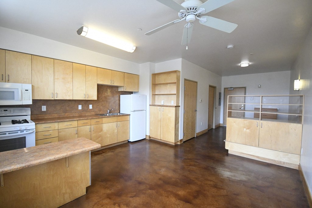 an empty kitchen with wooden cabinets and a refrigerator