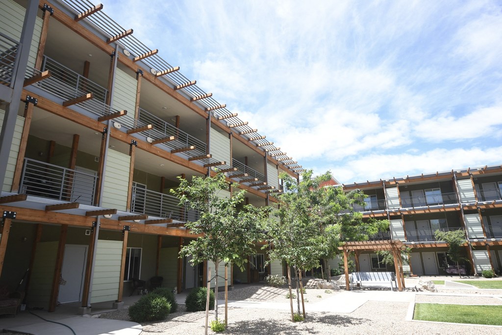 an apartment building with a courtyard and trees in front of it
