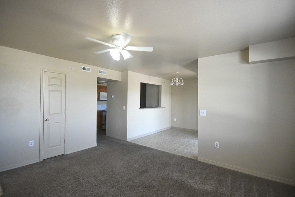 an empty living room with a ceiling fan and a tv
