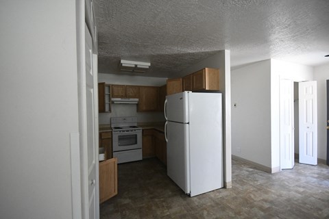 an empty kitchen with a refrigerator and a stove in it