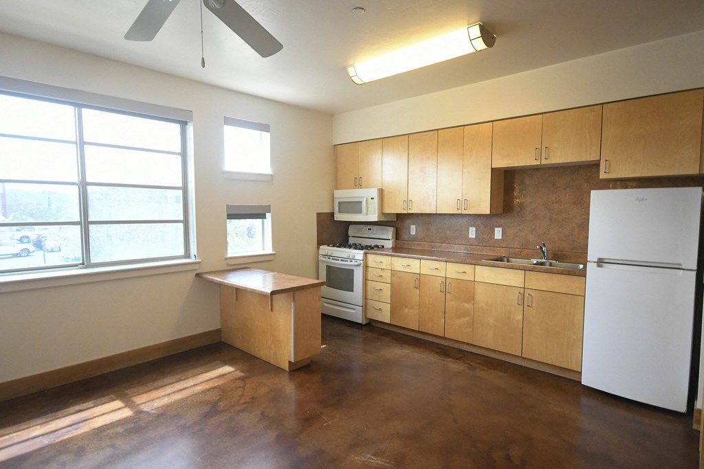 an empty kitchen with wooden cabinets and a white refrigerator
