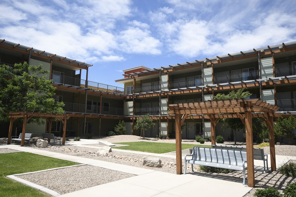a large building with a lawn and benches in front of it