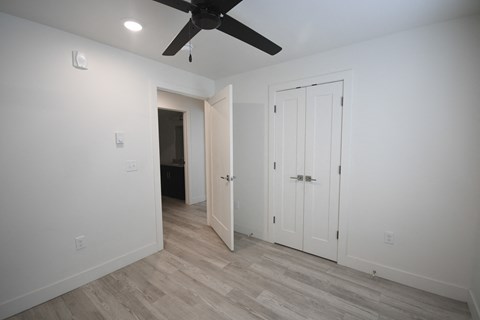 a bedroom with white walls and a ceiling fan