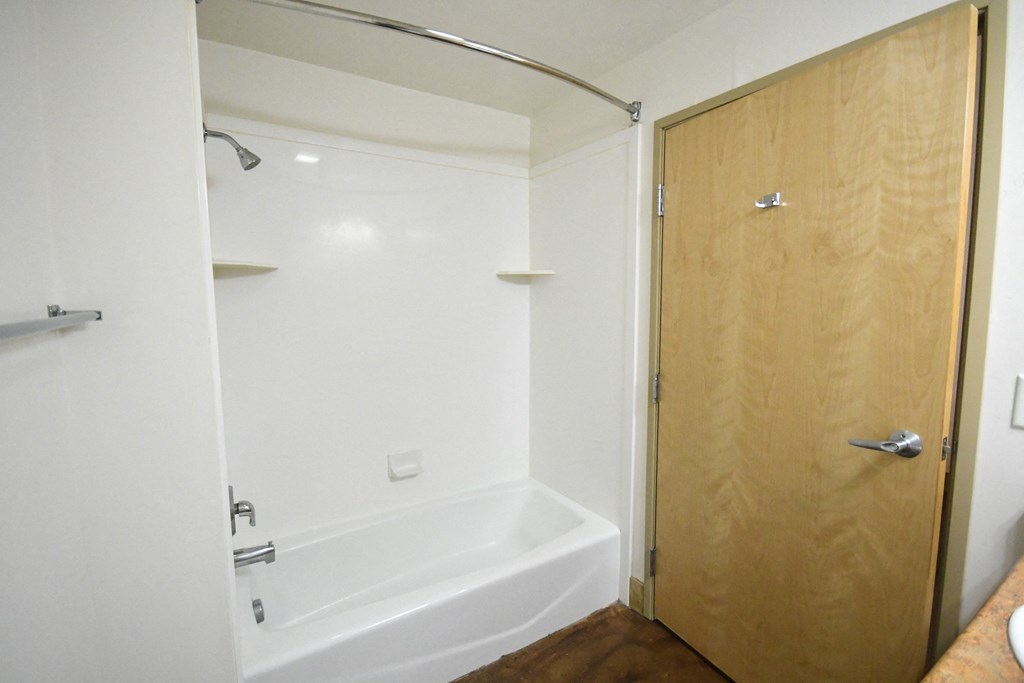 a bathroom with a white shower and a wooden door