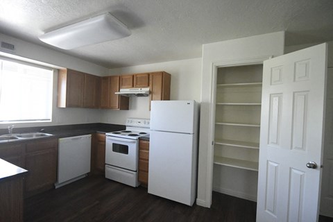 an empty kitchen with white appliances and wooden cabinets