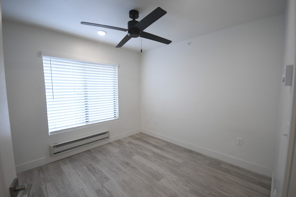 an empty room with a ceiling fan and a window