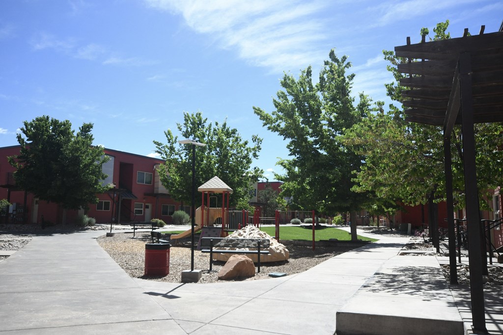 a park with a playground and trees in front of a building
