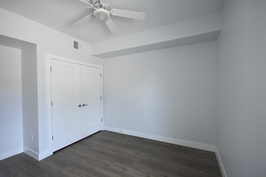 a bedroom with white walls and a ceiling fan