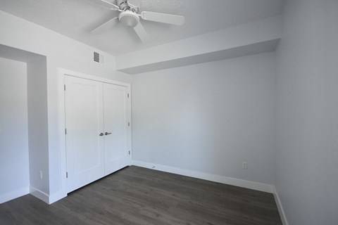 a bedroom with white walls and a ceiling fan