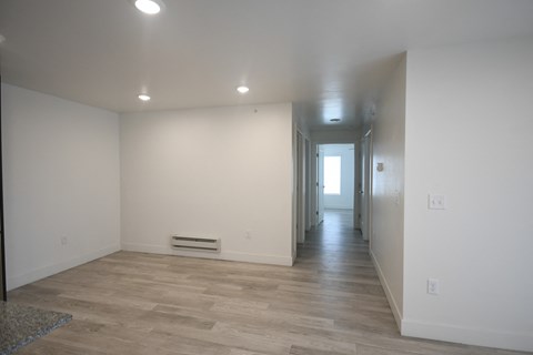 a living room and hallway with white walls and wood flooring