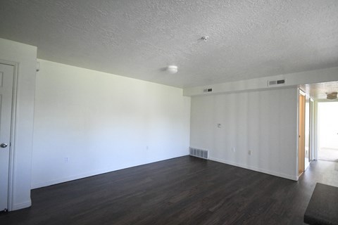 an empty living room with white walls and wood floors