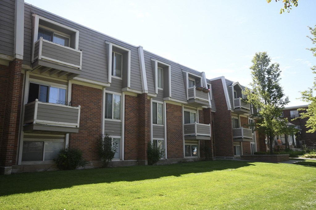 an apartment building with a green lawn in front of it