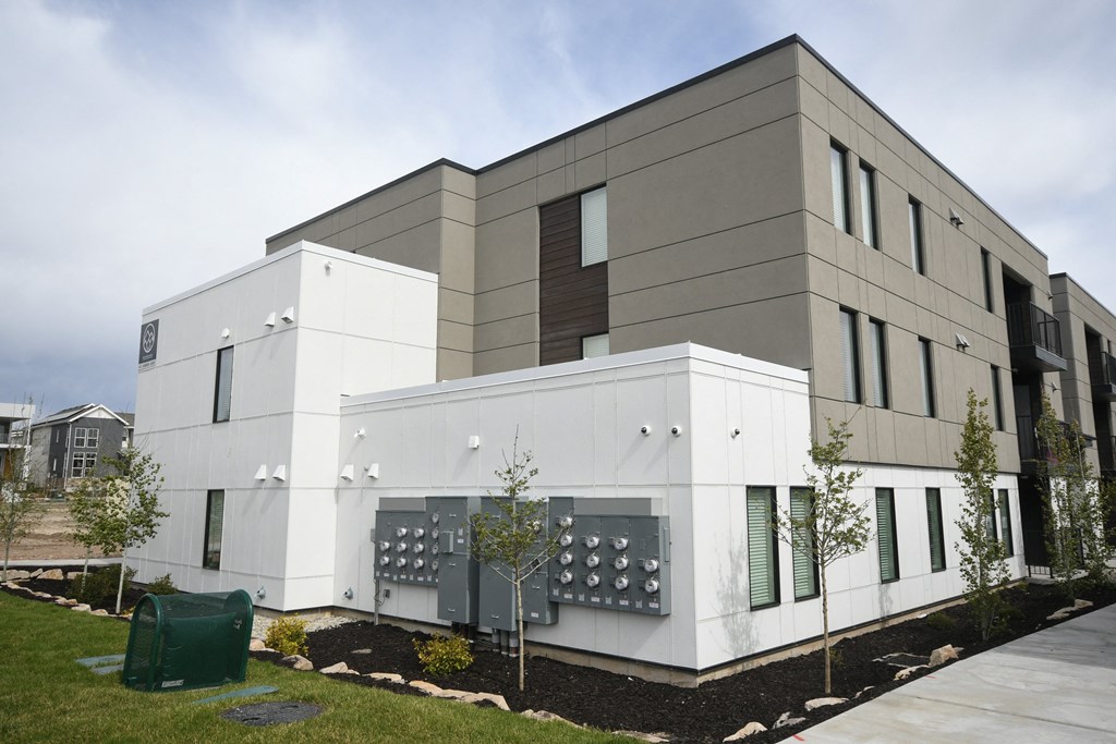 a white building with a sidewalk and trees in front of it