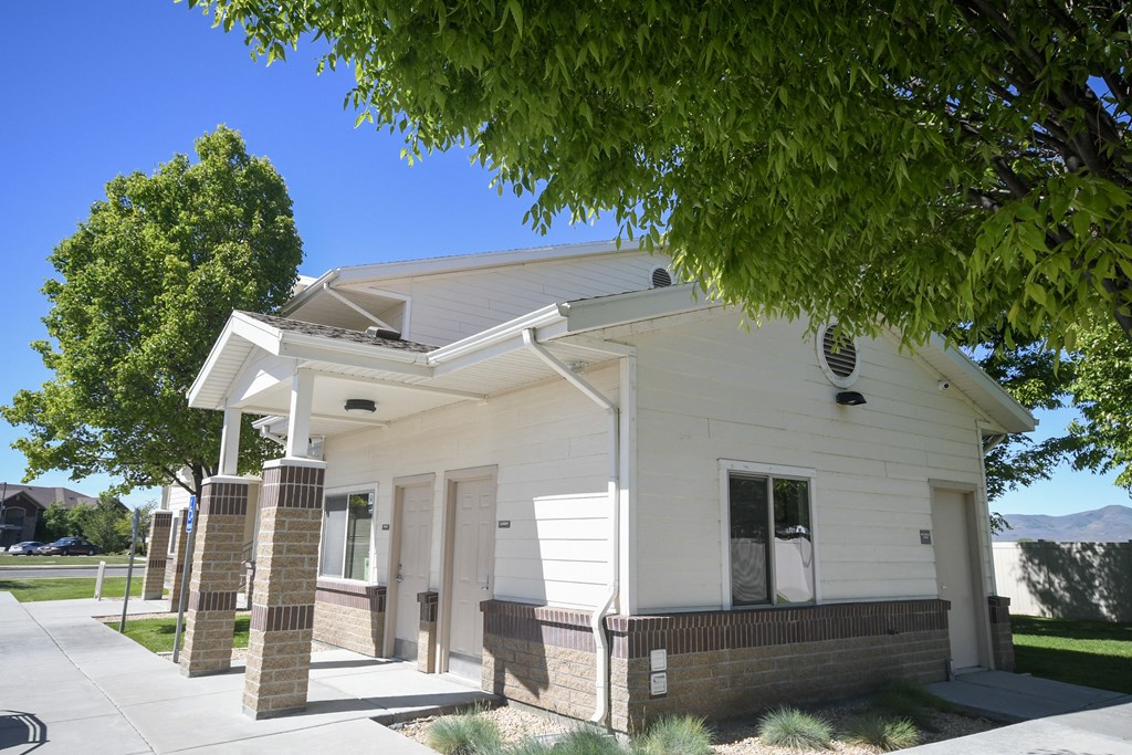 a white building with a porch and a tree