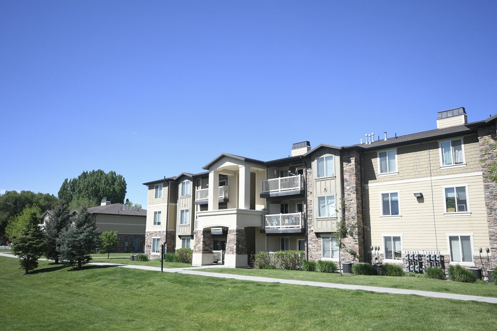 a row of apartment buildings on a sidewalk next to a grass field