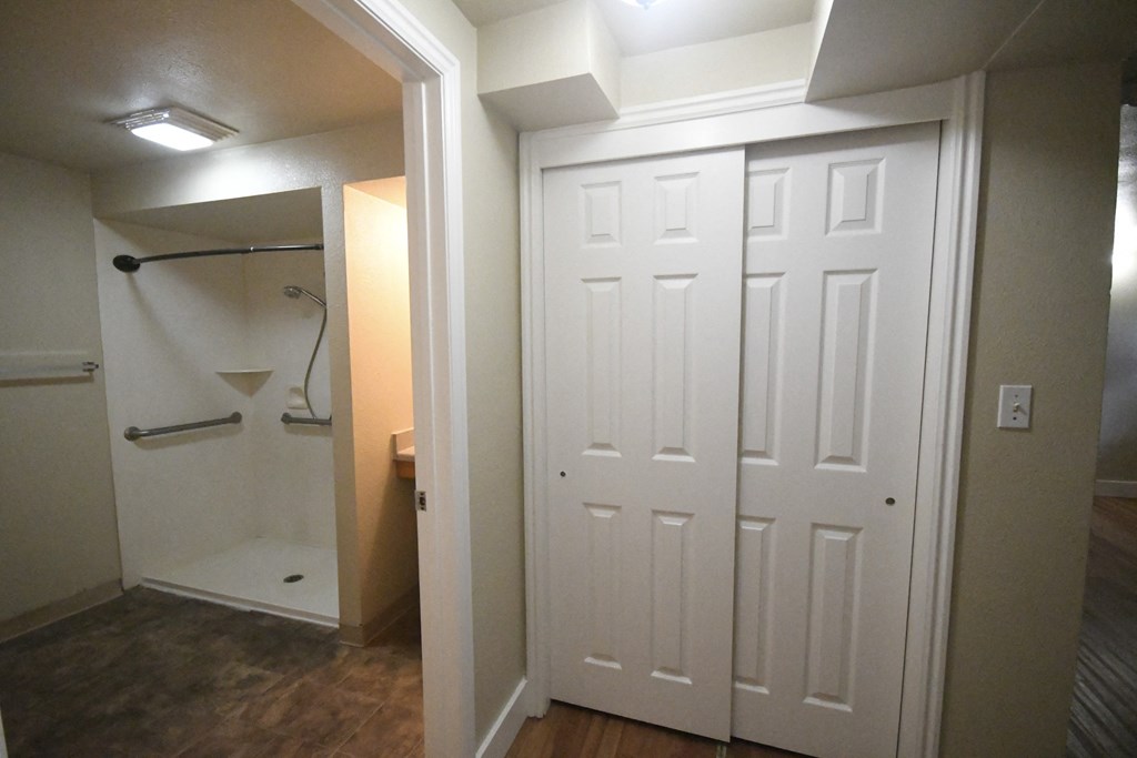 a bathroom with a closet and a shower and a white door